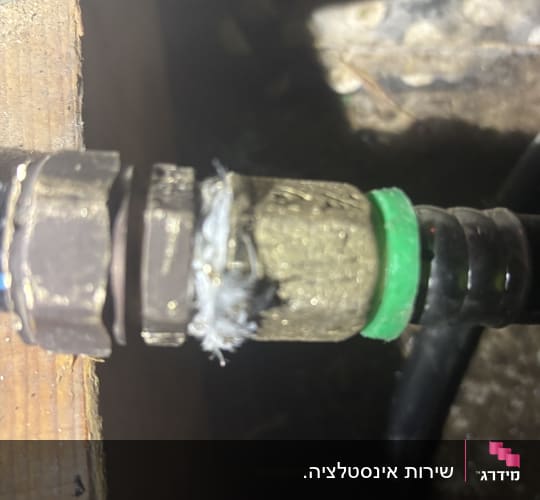 חיבור צינור עם אטם ירוק ועץ ברקע